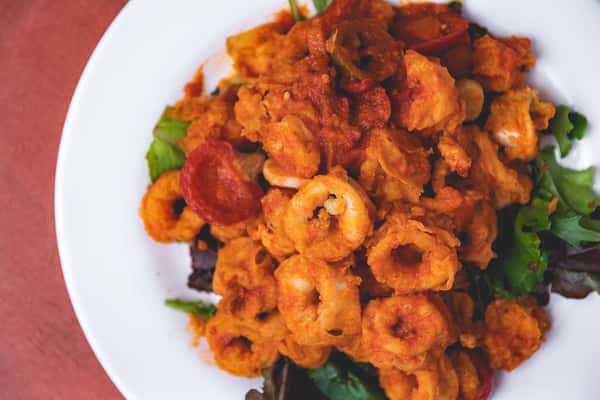 Golden fried calamari rings and tentacles with peppers, served over fresh greens at Pasta Lovers Trattoria.