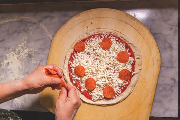 Chef preparing fresh Italian pasta inside a hollowed-out Parmesan cheese wheel, using metal utensils to mix the pasta with melted cheese at Pasta Lovers Trattoria in Times Square, NYC.