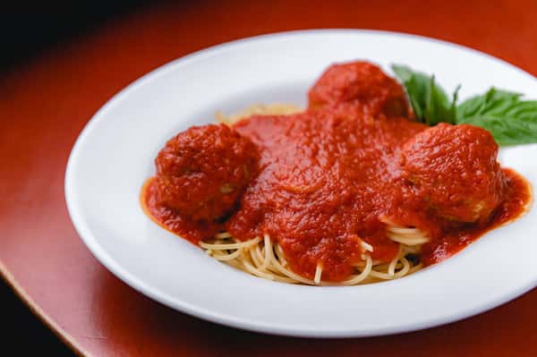 Classic Italian spaghetti topped with meatballs, rich tomato marinara sauce, and fresh basil at Pasta Lovers Trattoria in Midtown Manhattan, NYC.