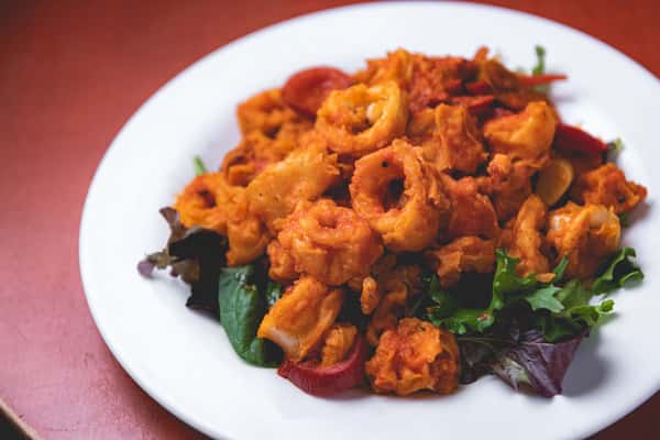 Crispy fried calamari with peppers and fresh herbs, served on a white plate at Pasta Lovers Trattoria.
