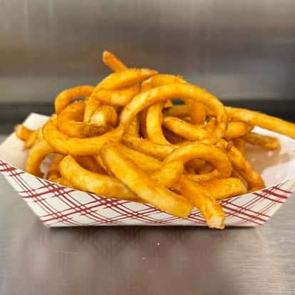 Crispy golden curly fries served in a red-and-white checkered paper tray on a stainless steel surface.