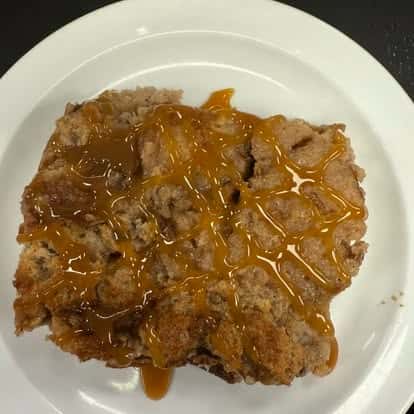 A slice of cake drizzled with caramel syrup, served on a white plate.