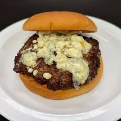 A cheeseburger with a grilled beef patty topped with melted blue cheese on a soft sandwich bun.