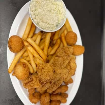 A plate with crispy fried chicken tenders, French fries, hushpuppies, and a side of coleslaw.