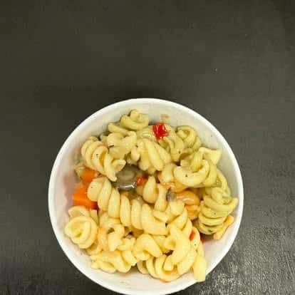 A bowl of colorful pasta salad with spiral pasta, mixed vegetables, and a light dressing.