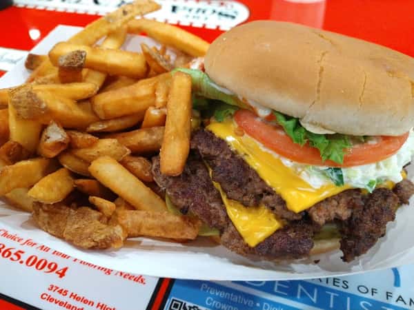 Cheeseburger with lettuce, tomato, and mayonnaise, served with a side of crispy French fries on a red tray.