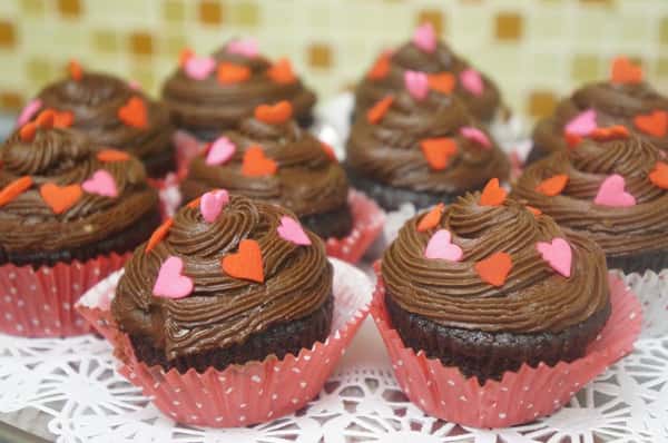 chocolate cupcakes with chocolate icing and heart-shaped sprinkles