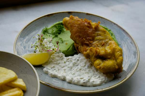 Tasty fish and chips served with tartar sauce and mushy peas.