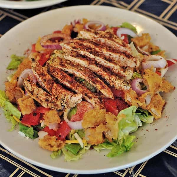 grilled chicken breast seasoned with rub sliced thin atop a large tossed salad with tomatoes, cheese, onions and croutons.