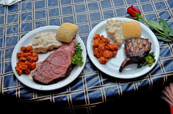 two dishes on a table with grilled meat with a side of mashed potatoes, biscuit and sweet potatoes