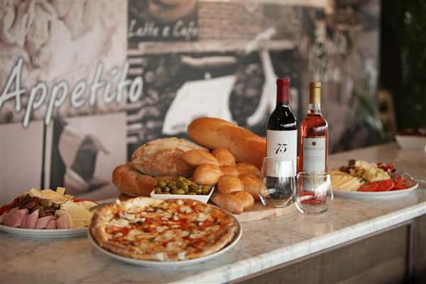 an assortment of pizza, bread and wine bottles on a counter
