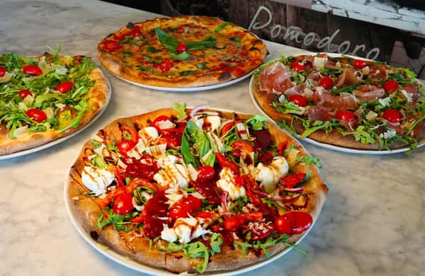 4 different specialty pizza pies on a table