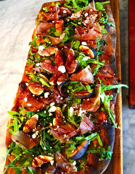 flatbread with arugula, Prosciutto, eggplant, and sprinkled cheese