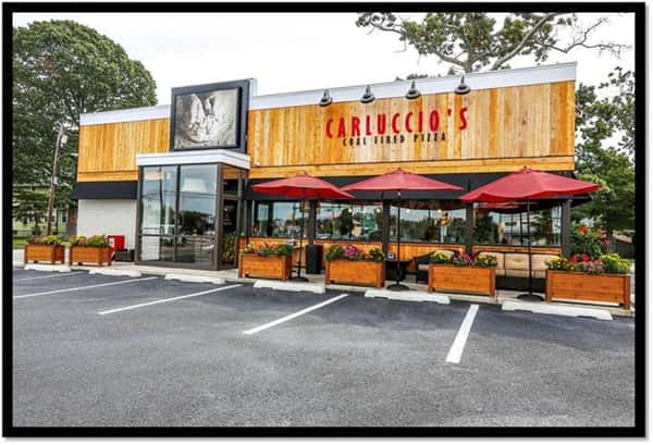 exterior building to carluccio's coal fired pizza showcasing their patio with chairs and umbrellas