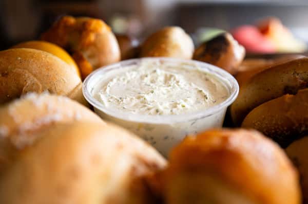 cream cheese spread served in a bowl surrounded by fresh bagels