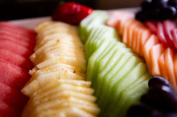 sliced fresh fruit including apples, kiwi, and strawberries arranged on a platter