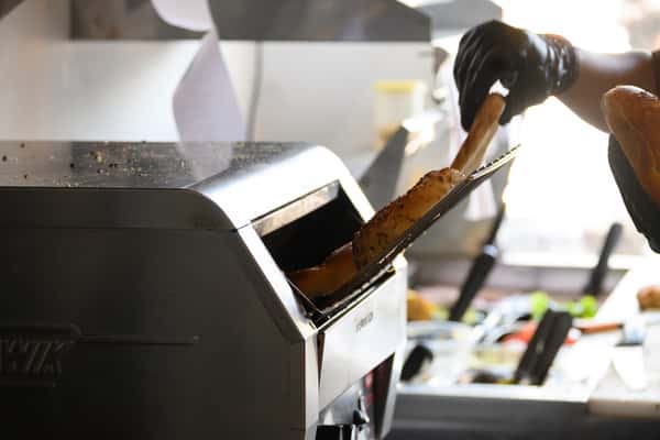 Worker placing freshly toasted bagels into a commercial toaster in a deli kitchen