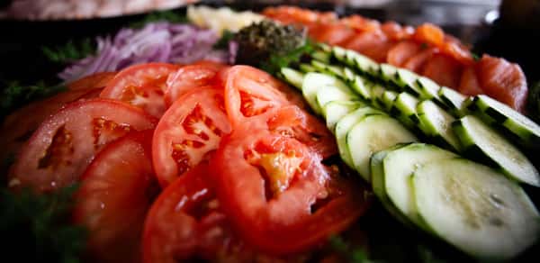 sliced tomatoes and cucumbers arranged over fresh greens in a salad platter
