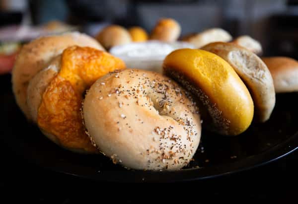 assorted fresh bagels including plain and seeded varieties on a tray