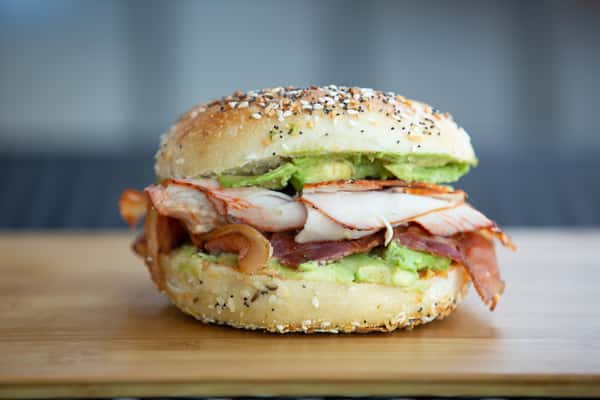 bagel sandwich with sliced turkey, bacon, lettuce, and tomato on a toasted everything bagel