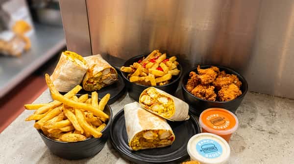 Chicken wraps, fries, and dipping sauces on a tray