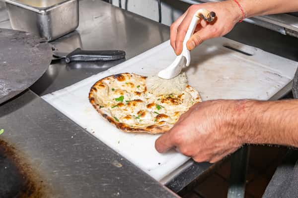 Chef brushing butter on garlic naan