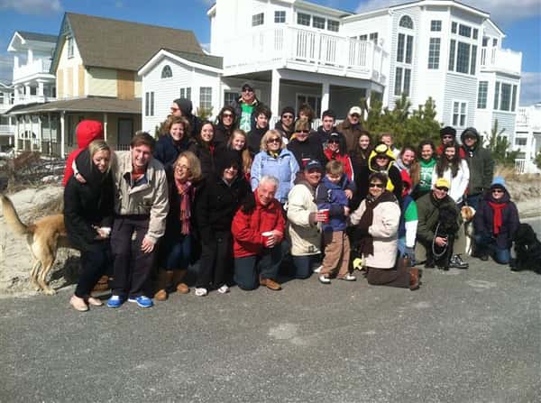 People taking a group photo in front of shoreside houses