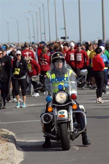 Police motorcycle leading crowd of people