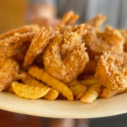 Plate of crispy golden fried shrimp paired with crinkle-cut fries, showcasing classic Southern comfort food.