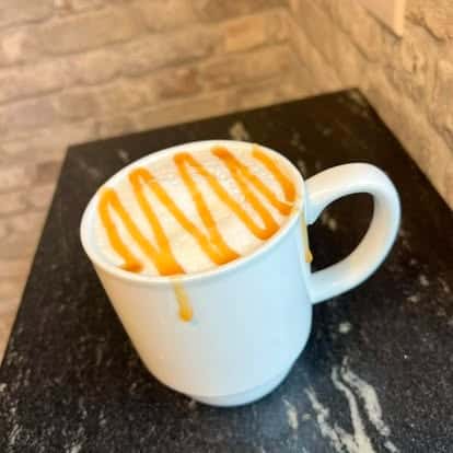 White mug of latte topped with caramel drizzle