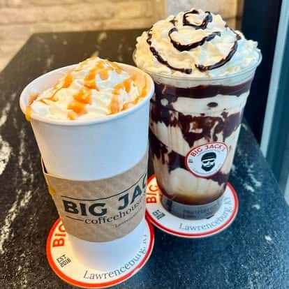 Two iced coffee drinks topped with whipped cream and caramel or chocolate drizzle