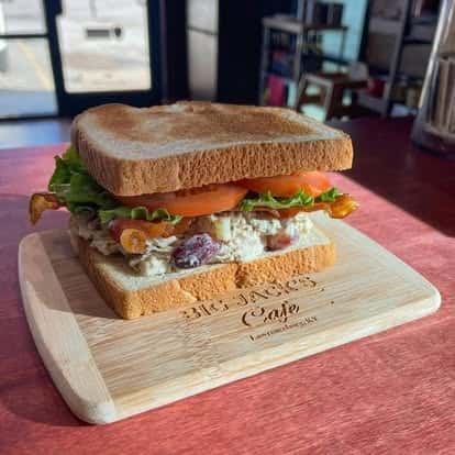 Turkey sandwich with lettuce and tomato on wheat bread, served on a wooden board