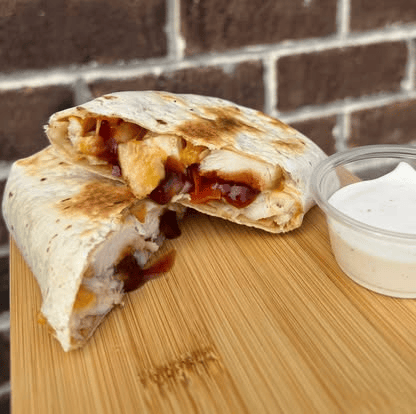 Chicken and berry quesadilla wrap cut in half, served with a side of dip