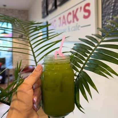 Hand holding a green smoothie in a mason jar with a straw
