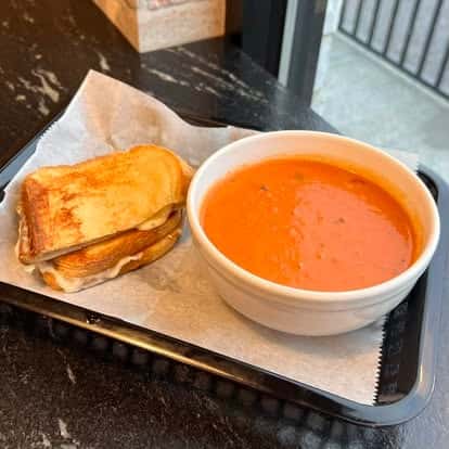 Grilled cheese sandwich cut into triangles, served with a cup of tomato soup
