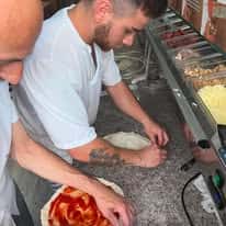 Pizza chefs preparing fresh pizzas by hand at a restaurant kitchen prep station