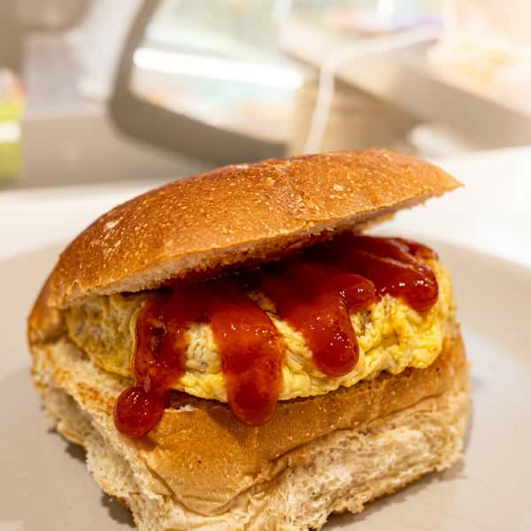 Breakfast sandwich with fluffy scrambled eggs and ketchup on a toasted rustic roll