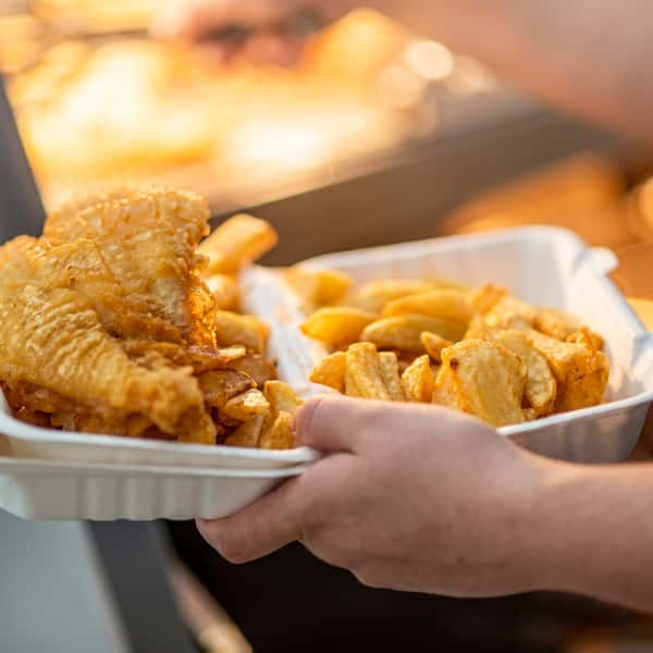 Freshly prepared battered fish and thick-cut chips served in takeaway trays