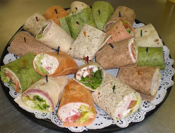 Platter with different wraps filled with cheese, deli meats and lettuce Available on white, wheat, spinach or tomato basil wraps