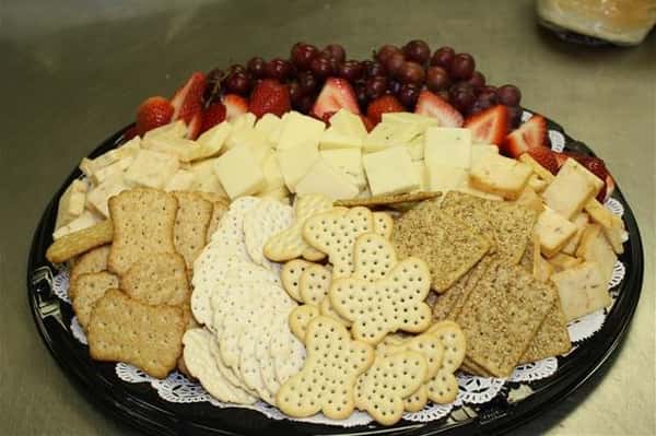 Platter with crackers, assorted cheeses, strawberries and red grapes