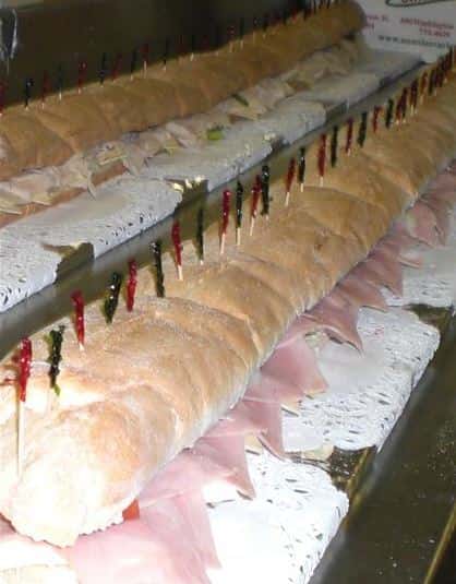 Hero sub with deli meats and cheese cut on a table with toothpicks in each slice