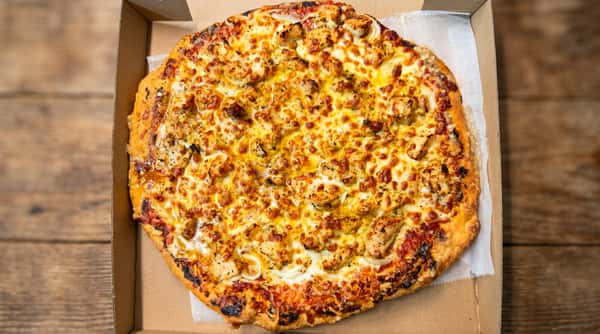 Chicken and onion pizza with melted cheese and a golden crust in a cardboard box.