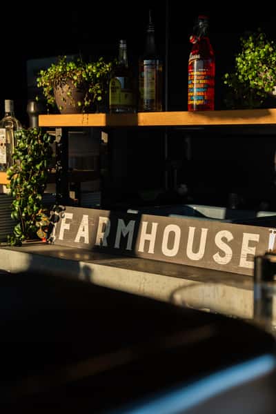 Farmbar signage on a couch. There is a bar behind the couch and a real live plant next to it.