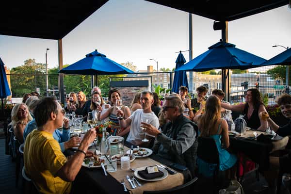 People cheersing on a rooftop with blue umbrellas. Busy and energetic rooftop in Chicago