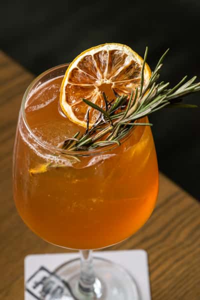 Farm Bar's Sangria garnished with dried citrus and fresh rosemary. Served in a wide mouth wine glass over ice.