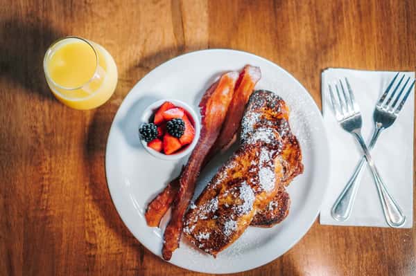 Breakfast with bacon, orange juice, and a fresh fruit cup