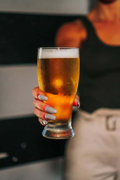Bartender holding out a cold glass filled with beer from a tap