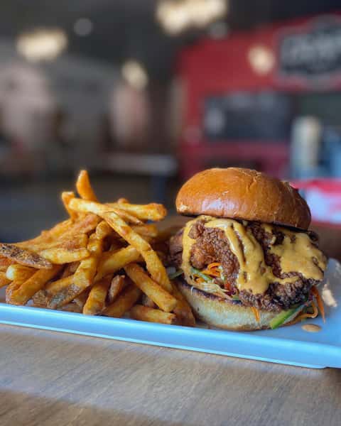 Stacked hamburger with melty cheese and crisp fries on a light blue plate.