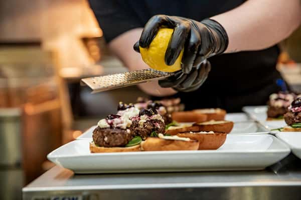 Chef using a hand grater to zest lemon over an entree