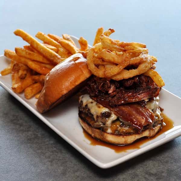 Large stacked hamburger with fried onions, bacon and crispy fries